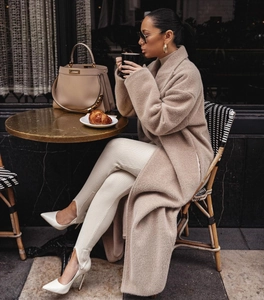Détail d'un manteau en laine camel porté avec un legging côtelé blanc et des talons hauts