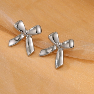 Polished silver bow earrings in high-grade stainless steel on orange silk background