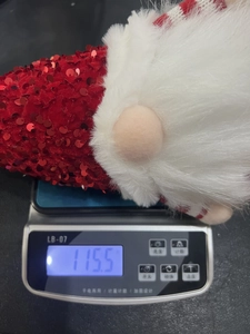 Détail montrant le poids de 115,5g du gnome de Noël lumineux sur une balance numérique