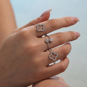 Bague ouverte argentée élégante avec trois trèfles sertis de zircons sur la main