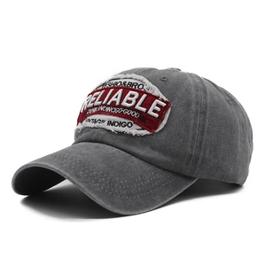 Detailed macro view of vintage washed grey cotton baseball cap with red embroidered patch