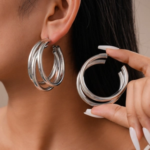 Silver multi-layered geometric C-shaped hoop earrings worn by model for a modern look