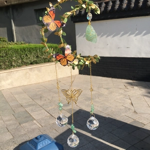 Detail of moon suncatcher with green leaves, crystal spheres and butterflies in sunlight