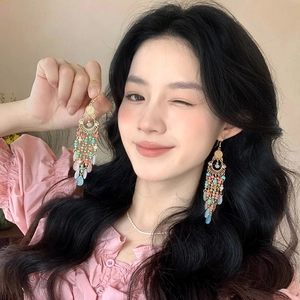 Bohemian colorful feather fringe tassel earrings with beads on model in beige setting