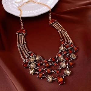 Detail view of a vintage gold necklace with deep red and champagne triangle rhinestones