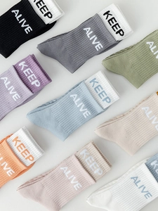 Flat lay view of colorful mid-calf yoga socks with KEEP ALIVE knitted text