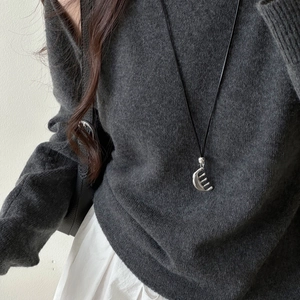 Detail of silver comb pendant necklace on grey knit sweater for minimalist style