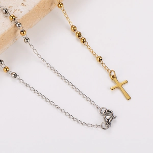 Detailed close-up of two-tone beaded chain necklace with a small metal cross pendant