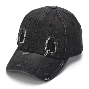 Detail of black washed denim baseball cap featuring distressed holes and white stitching