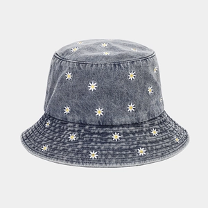 Close-up of small white daisy embroidery on gray washed denim bucket hat fabric