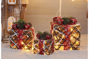 Close-up of rustic woven rattan Christmas gift boxes with red ribbons and LED lights