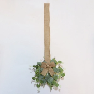 Detail of faux eucalyptus wreath with white flowers and burlap bow on white background