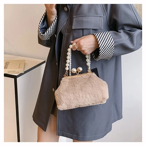 Detailed shot of beige faux fur handbag featuring pearl handle and gold metal frame clasp