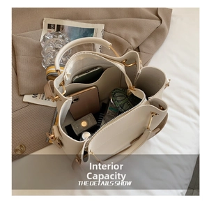 Spacious interior of minimalist cream bucket bag with zip compartment and golden hardware
