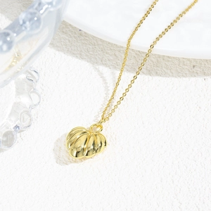 Macro shot of 18k gold plated hollow heart pendant with textured finish on white background