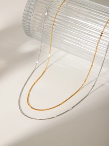 Detail of minimalist gold and silver plated stainless steel flat curb link necklaces