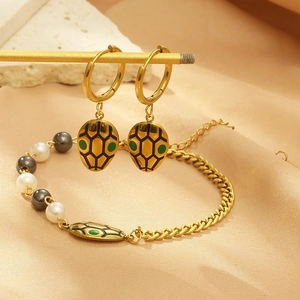 Detail of gold snake earrings and matching pearl bracelet set on silk background