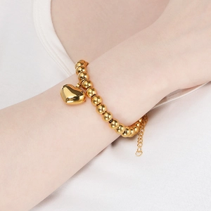 Detail of 18K gold plated beaded bracelet with polished heart pendant on a model wrist