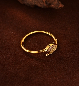 Macro shot of gold snake-shaped ring with marquise cut crystal and pave zircon details