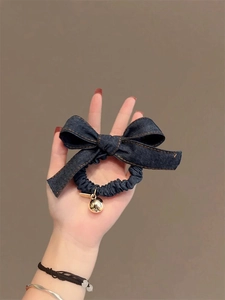 Vue détaillée d'un chouchou en denim bleu foncé avec un nœud et un pendentif cœur en métal