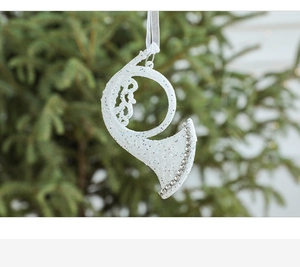 Close-up of white glittery horn Christmas ornament with silver beads on a festive tree