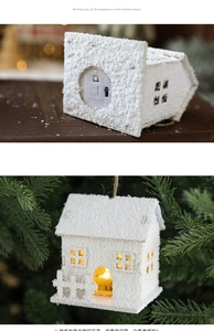 Macro detail of a white LED snowy house ornament showing battery switch and tree hanging effect