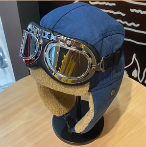 Dettaglio del cappello aviatore blu con occhiali argento e fodera in pile beige