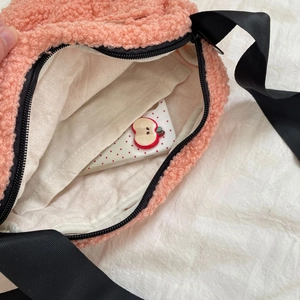 Detail view of pink plush crossbody bag featuring canvas lining and interior pocket