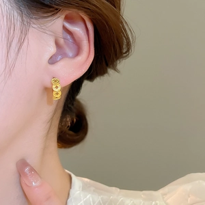 Detail view of 18k gold plated hoop earrings with vintage copper coin pattern on model