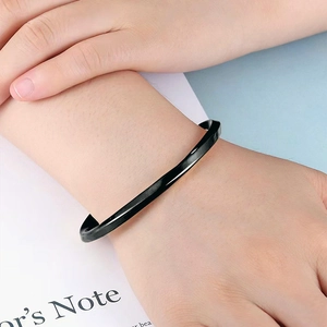 Close-up of a black Mobius twist titanium steel bangle on a model's wrist with modern aesthetic