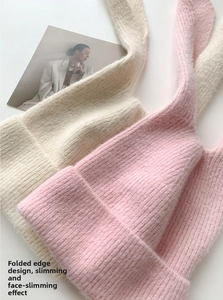 Close-up of knit rabbit ear hats in cream and pink colors with soft fuzzy texture