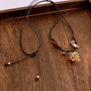 Collier vintage en cordon tressé avec pendentif pomme de pin dorée sur plateau