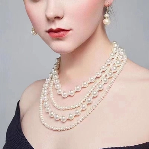 Detail shot of elegant four-layer pearl necklace and matching earrings on a model