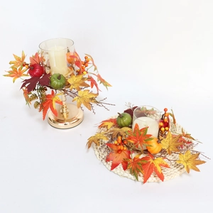 Close-up of fall candle holders featuring artificial maple leaves, pumpkins and berries