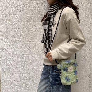 Detail of plush crossbody bag with blue floral pattern and striped shoulder strap