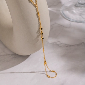 Detail of 18K gold chain with black zircon gemstones and small metal tube accents
