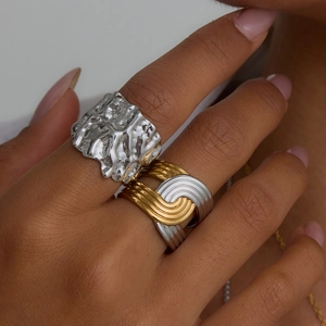 Detail view of silver lava texture and bicolor streamline wavy rings on a hand