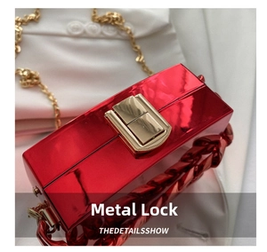 Close-up of bright red mirrored box bag featuring gold push-lock and dual texture chains
