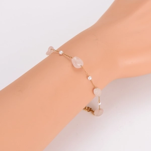 Gold chain bracelet with irregular pink stones and small white pearls on a wrist