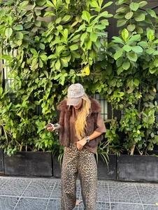 Detail van een bruin vest van imitatiebont gecombineerd met een trendy broek met luipaardprint