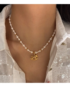Detail of elegant pearl necklace with a gold pony pendant on a model's neck