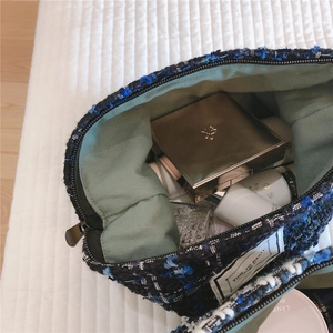 Macro detail of navy tweed makeup bag with Time to Party tag and interior lining