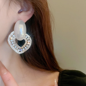 Detailed view of oversized pearl stud with rhinestone encrusted heart drop earring
