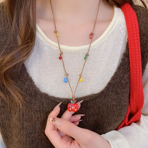 Gros plan d'un collier pendentif pomme rouge avec perles colorées sur cordon marron