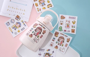 Detail view of a white insulated water bottle decorated with cute cartoon PVC stickers