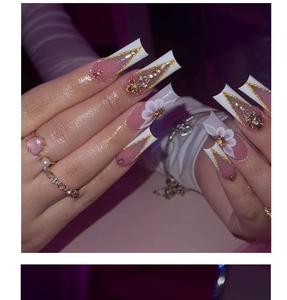 Macro detail of long coffin nails with 3D white flowers and sparkling rhinestones