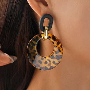 Close-up of geometric leopard print acrylic earrings worn by a model in a high-fashion shot