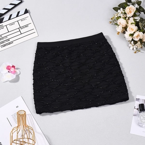 Détail d'une mini-jupe trapèze noire avec texture ondulée et fils dorés scintillants