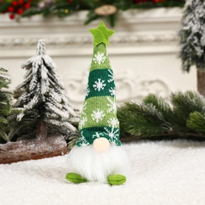 Detail of a lighted Christmas gnome with green snowflake hat and long white beard on snow