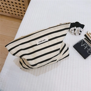Detail of striped cotton toiletry bag featuring simple wish tag on quilted fabric